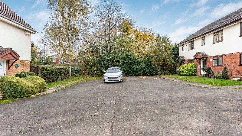 Shared driveway with parked car, hedges and residential properties on either side