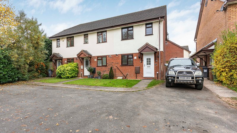 Semi-detached brick house with driveway, parked car, and front garden