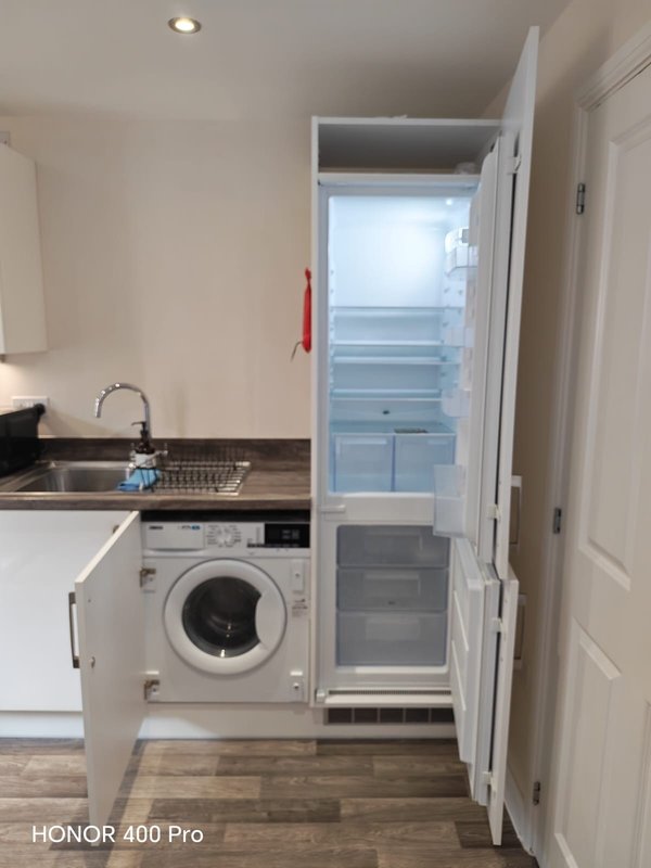 Compact kitchen with integrated washing machine, sink, and open refrigerator