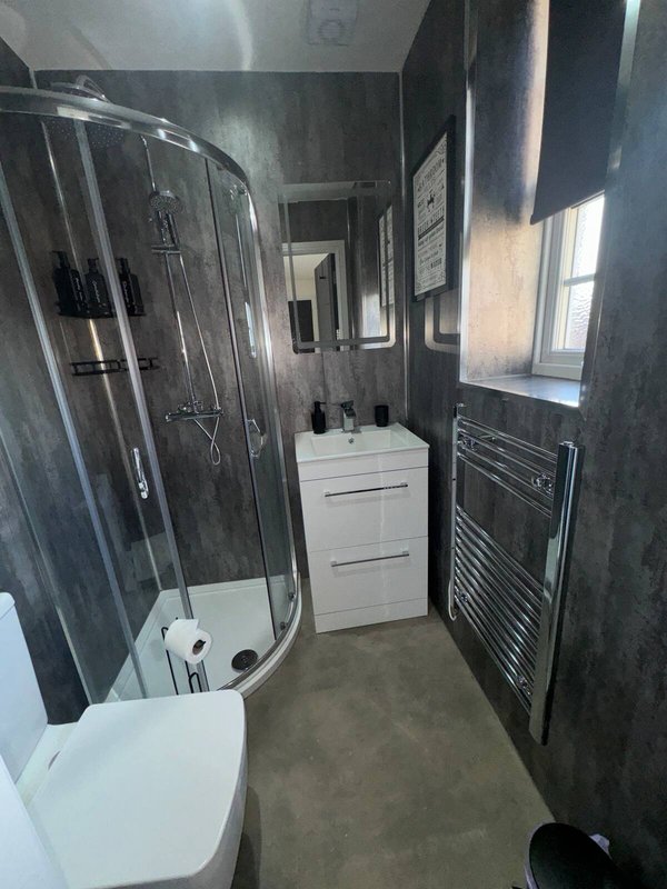 Modern bathroom with curved shower cubicle, white vanity unit, heated towel rail and window