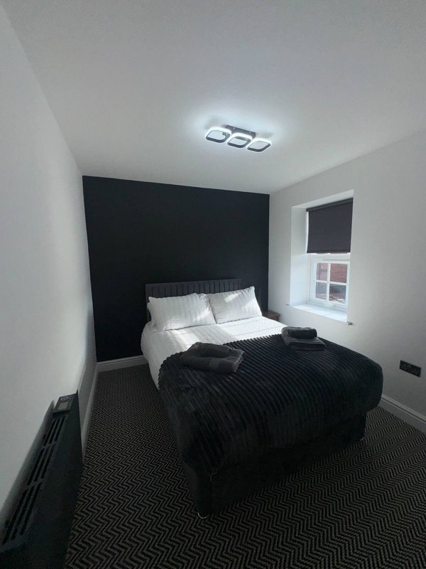Modern bedroom with double bed, black feature wall, white pillows and dark bedding