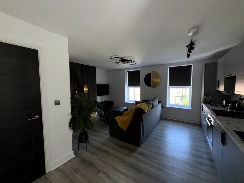 Open-plan living and kitchen area with grey sofa, wooden flooring, and modern furnishings
