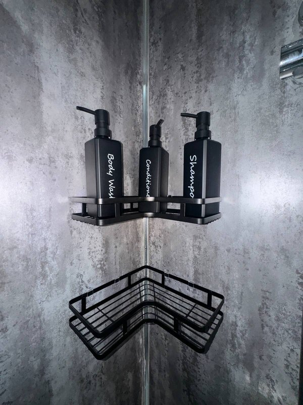 Bathroom corner shelf with three black pump bottles and wire basket organizer