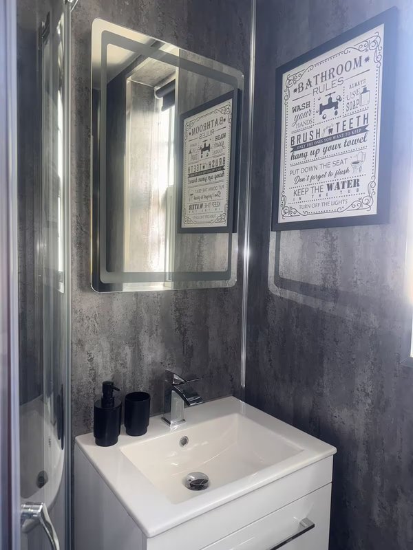 Modern bathroom with white sink, mirror, shower enclosure and decorative wall posters