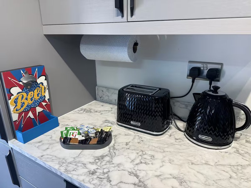 Kitchen counter with marble worktop, black toaster and kettle, paper towel holder, and decorative items