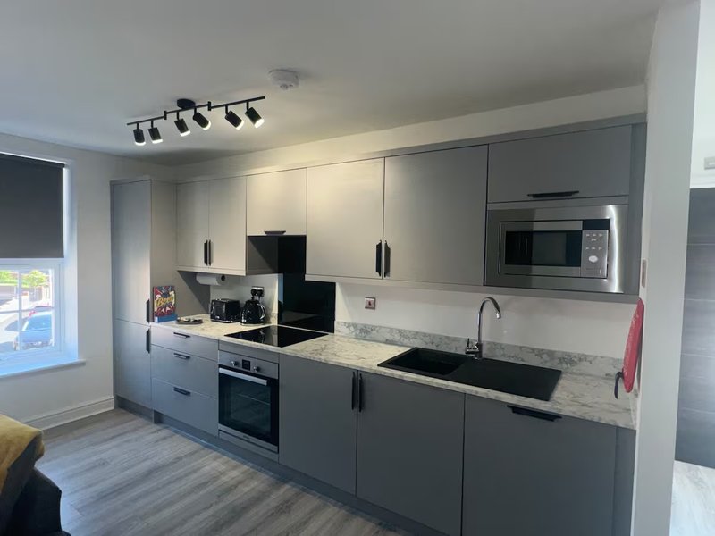 Modern kitchen with grey cabinetry, marble countertop, stainless steel appliances and window