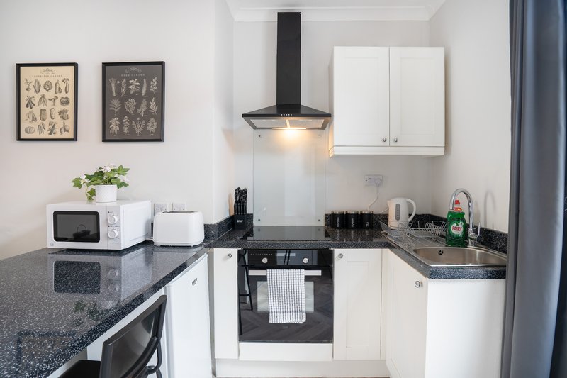 Modern white kitchen with black worktops, black range hood, built-in oven and wall art