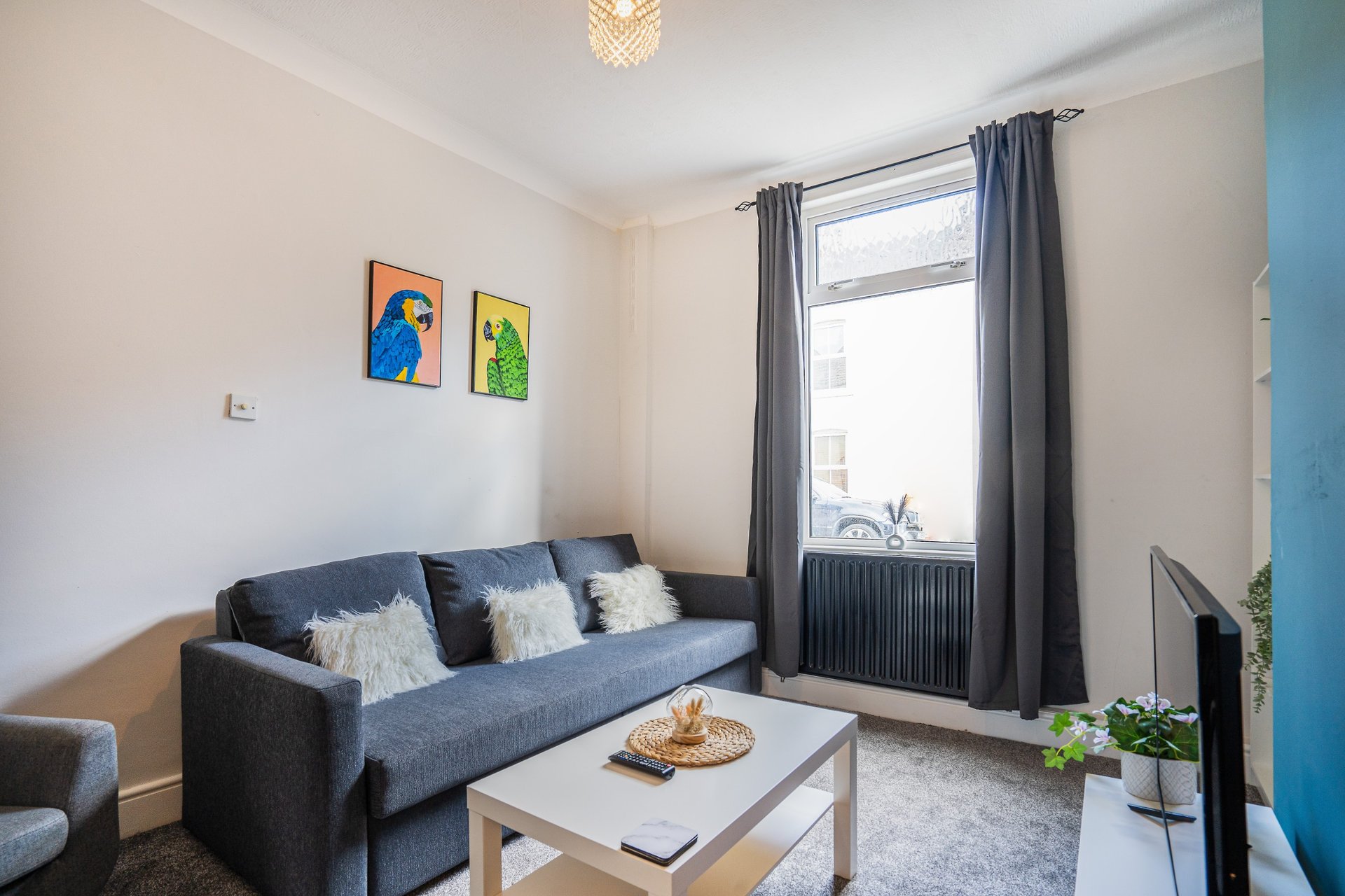 Modern living room with gray sofa, white coffee table, large window and wall art