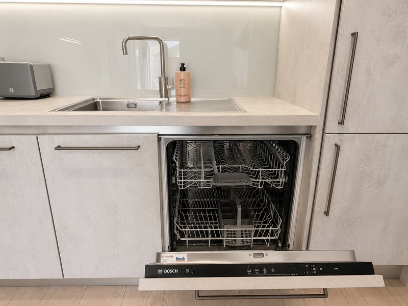 Modern kitchen with integrated dishwasher, stainless steel sink and faucet