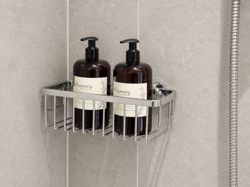 Bathroom shower shelf with two pump bottles and toiletries in chrome caddy