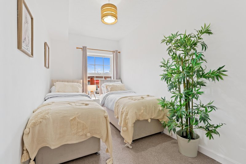 Twin bedroom with two single beds, potted plant, window with city view, and ceiling light