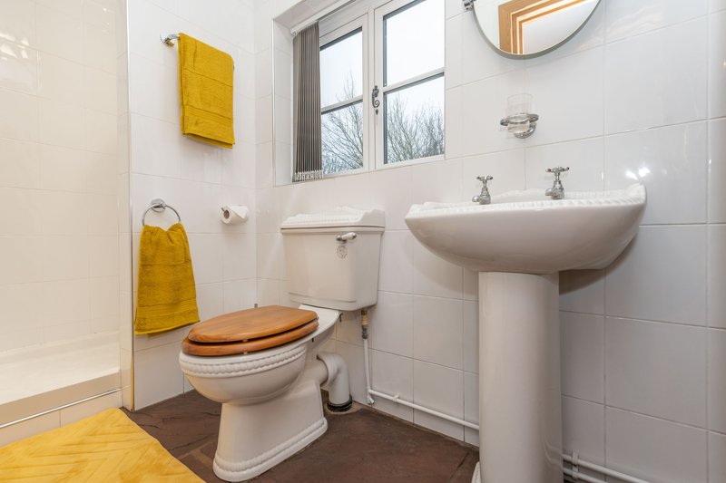 Bathroom with toilet, pedestal sink, mirror, yellow towels and window