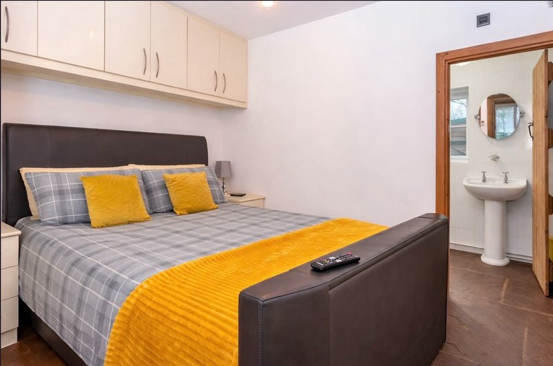 Bedroom with double TV Smart bed, yellow and grey bedding, built-in wardrobe, and ensuite bathroom visible.