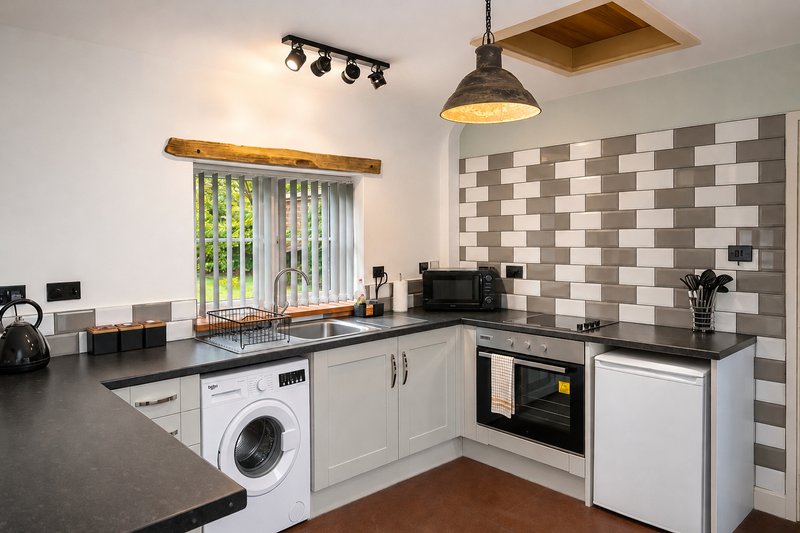 Modern kitchen with greycabinetry, black countertops, integrated appliances and tiled backsplash