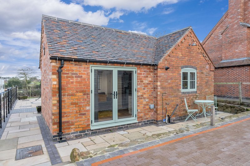 Red brick residential extension with double glass doors and paved patio area