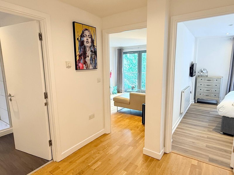 Bright hallway with wooden flooring, white doors, and contemporary wall art