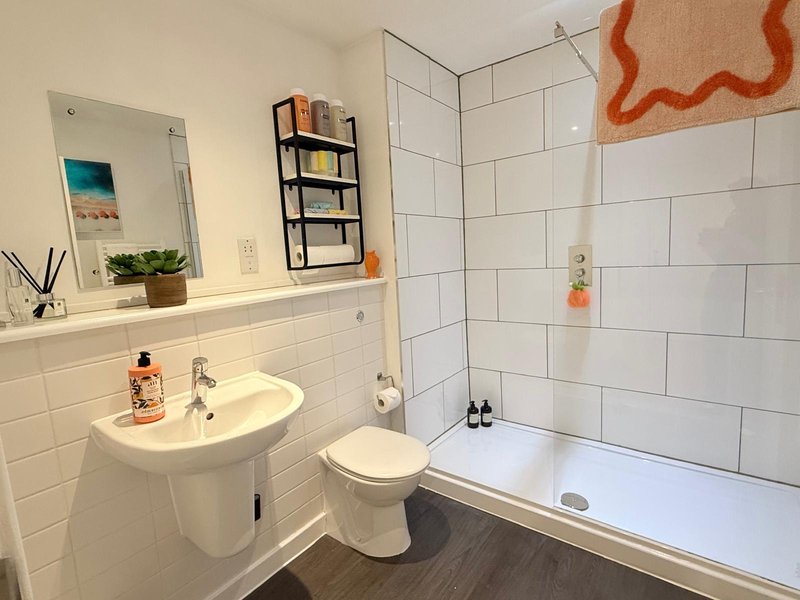 Bright bathroom with white subway tiles, pedestal sink, toilet, bath tub and mirror