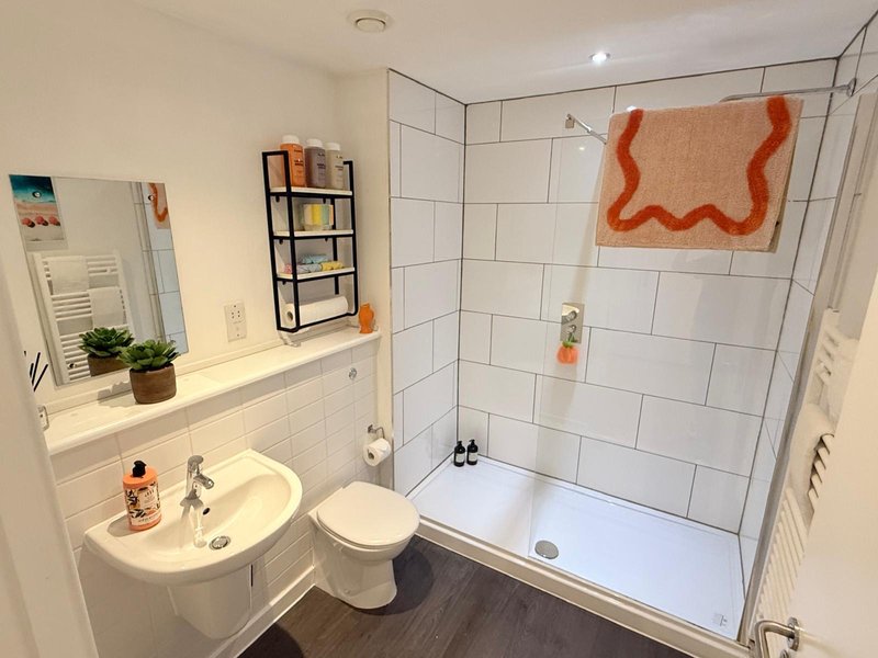Modern bathroom with white subway tile, walk-in shower, pedestal sink and toilet