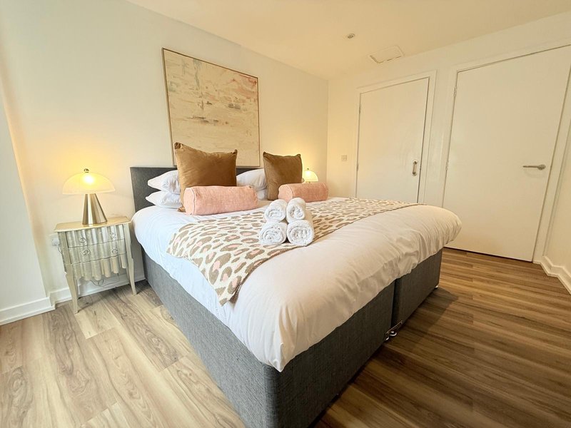 Modern bedroom with double bed, patterned bedding, wooden flooring and bedside lamp