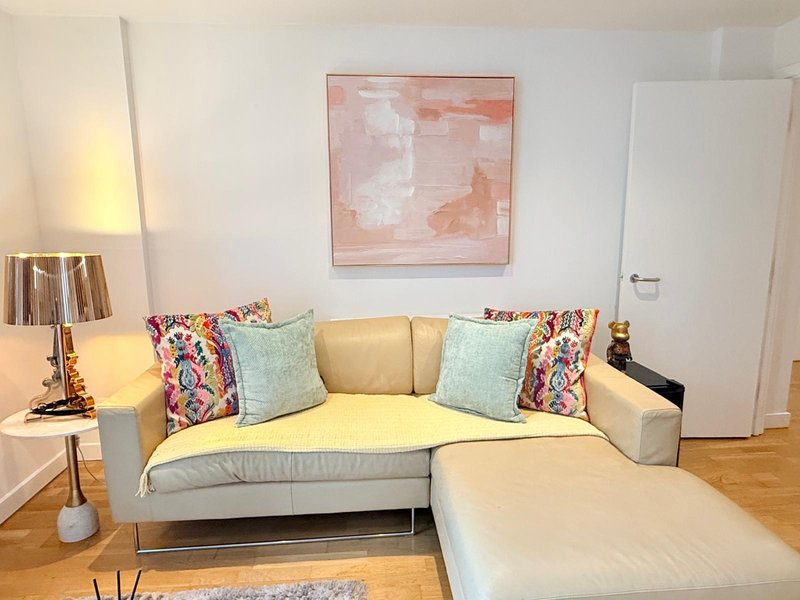 Modern living room with cream-colored sectional sofa, colorful throw pillows, and abstract wall art