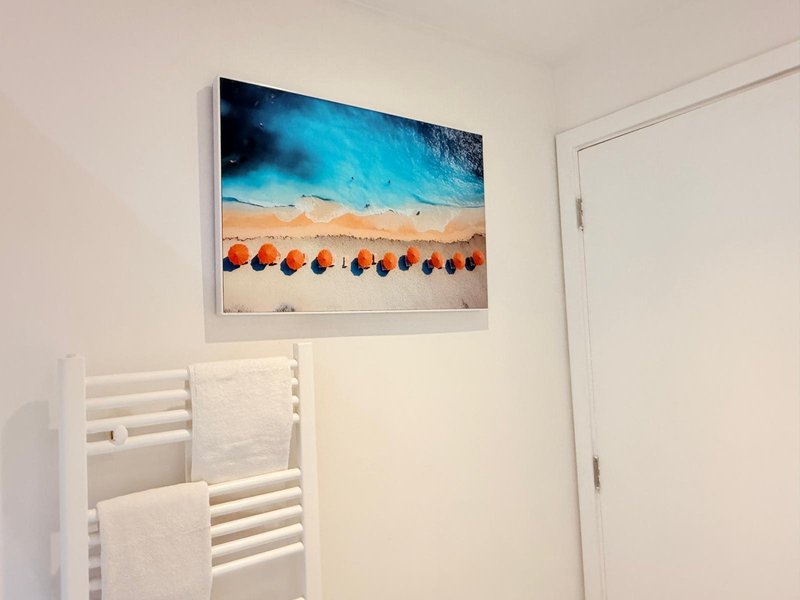 Bright bathroom with white towel rail, framed beach umbrella artwork on wall