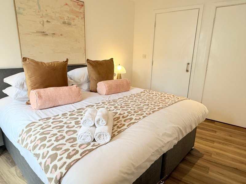 Modern bedroom with double bed, patterned bedding, decorative pillows and rolled towels