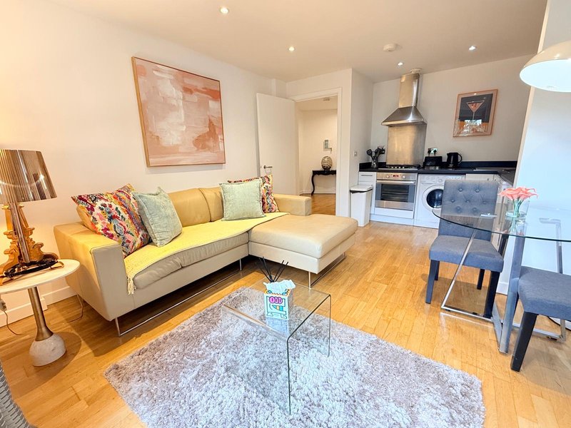 Open-plan living room with yellow sofa, dining area, kitchen, wooden flooring and modern decor