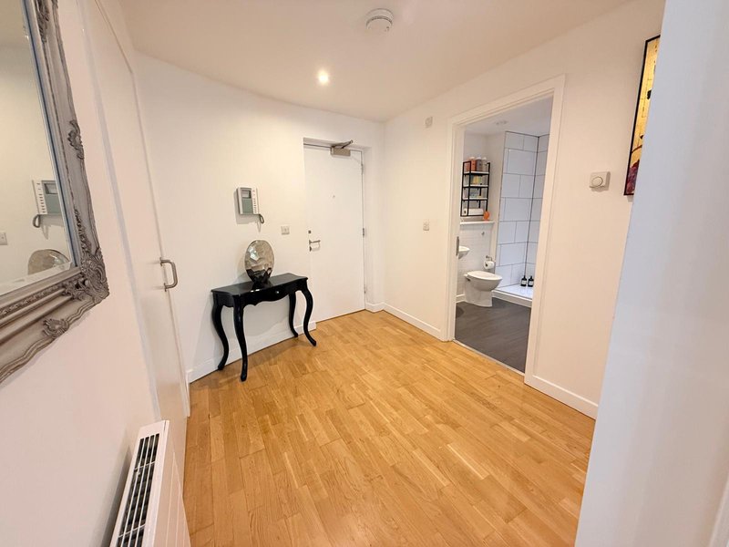 Bright hallway with wooden flooring, white walls, black console table and mirror