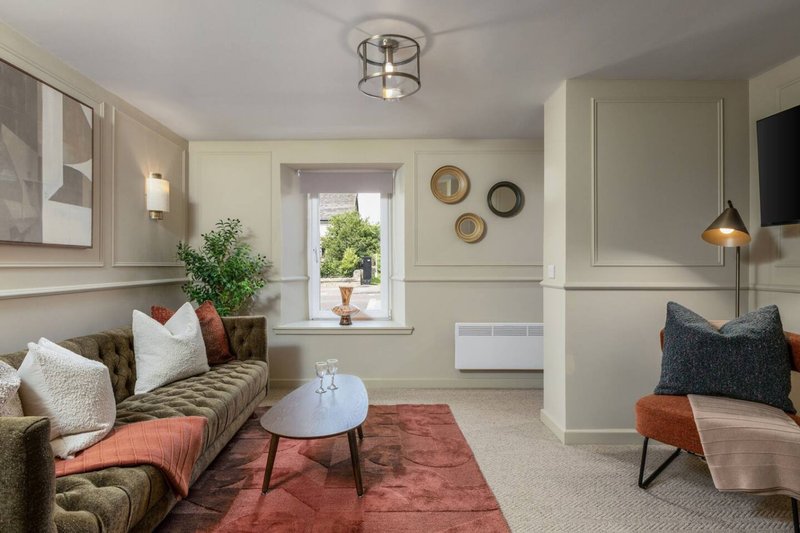 Bright living room with olive sofa, cushions, round coffee table and armchair