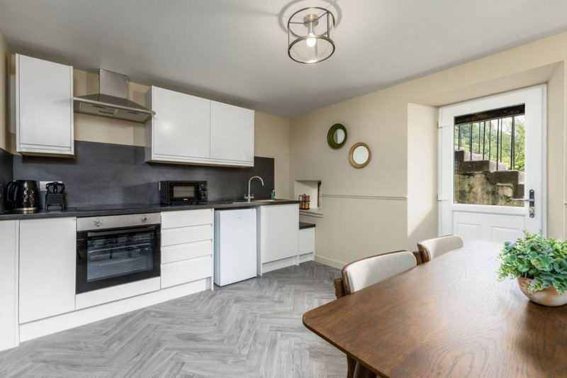 Modern kitchen with white cabinetry, dining table, and garden view through patio doors