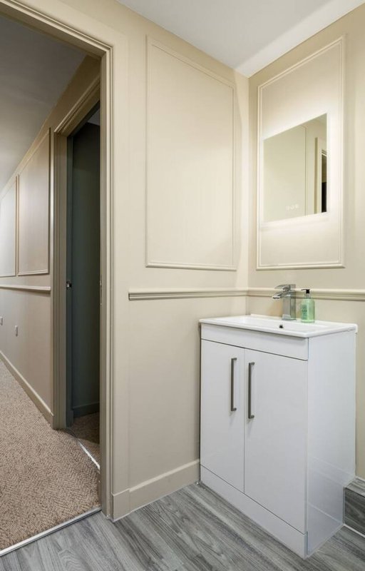 Modern bathroom with white vanity, mirror, sink and vinyl flooring