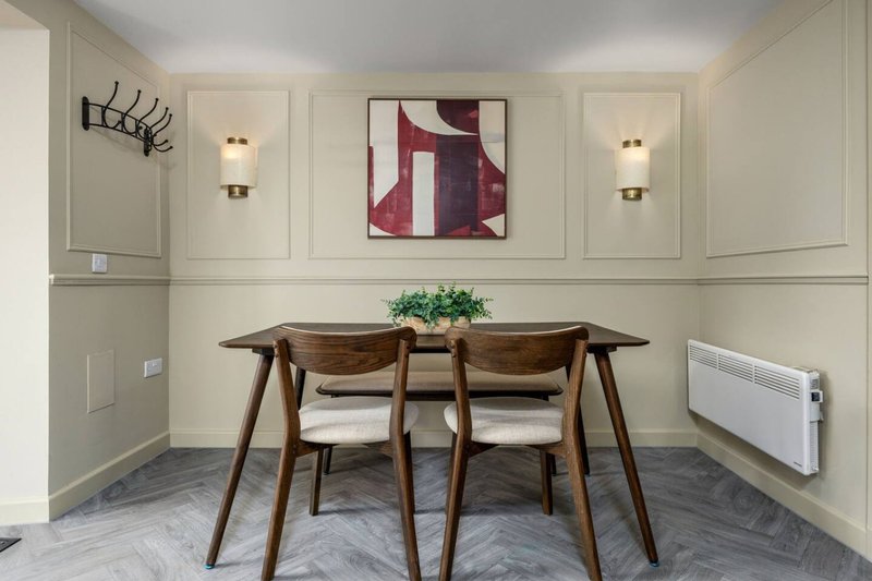 Modern dining room with wooden table, two chairs, abstract wall art, and pendant lighting