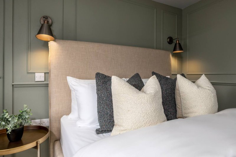 Modern bedroom with upholstered headboard, white bedding, decorative pillows and pendant lights