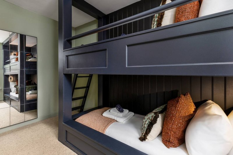 Modern bedroom with navy bunk bed, white bedding, copper cushions and built-in storage shelving