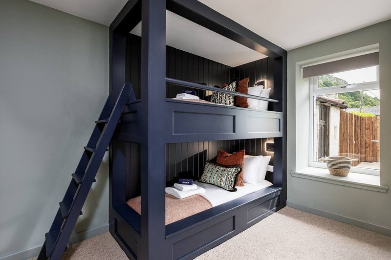 Modern bedroom with navy blue built-in bunk beds, bedding, pillows and small decorative items