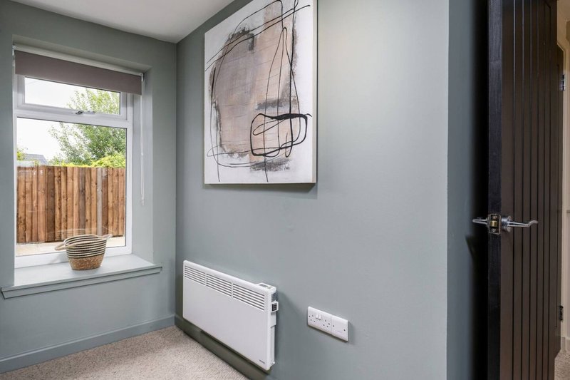 Light grey bedroom with window overlooking garden, wall art, radiator and door