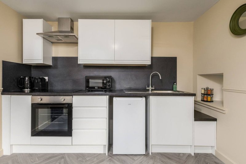 Modern kitchen with white cabinetry, black countertop, integrated appliances and stainless steel sink