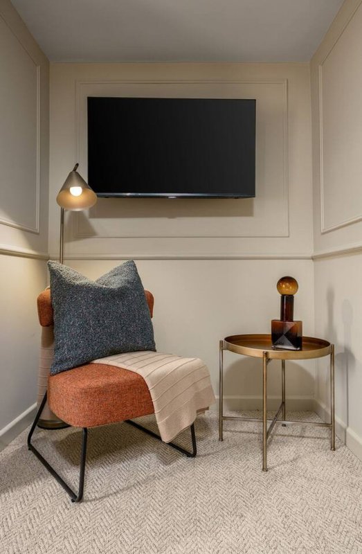 Modern sitting area with wall-mounted TV, upholstered chair, cushions, side table and pendant lamp