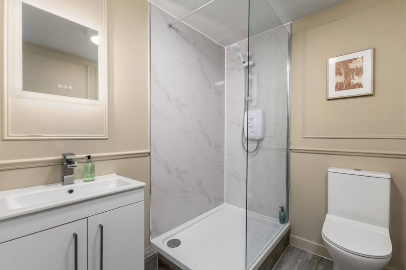 Modern bathroom with vanity, mirror, glass shower enclosure and toilet