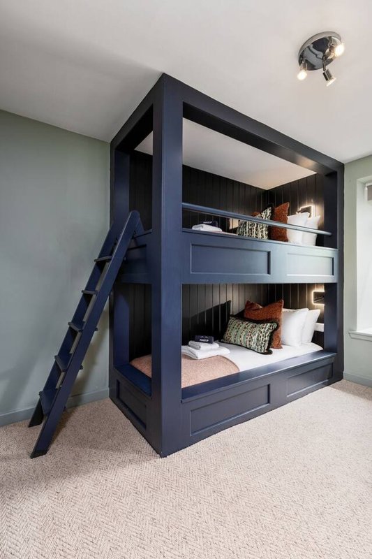 Modern navy bunk bed with ladder, two sleeping levels, built-in shelving and bedding