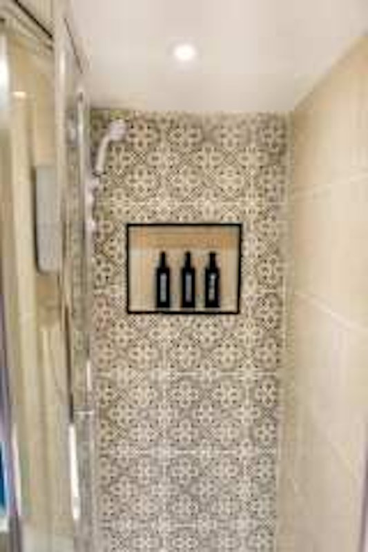 Bathroom shower area with mosaic tile walls and framed bottle decoration