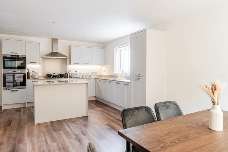 Modern kitchen with white cabinetry, island, and dining table with chairs