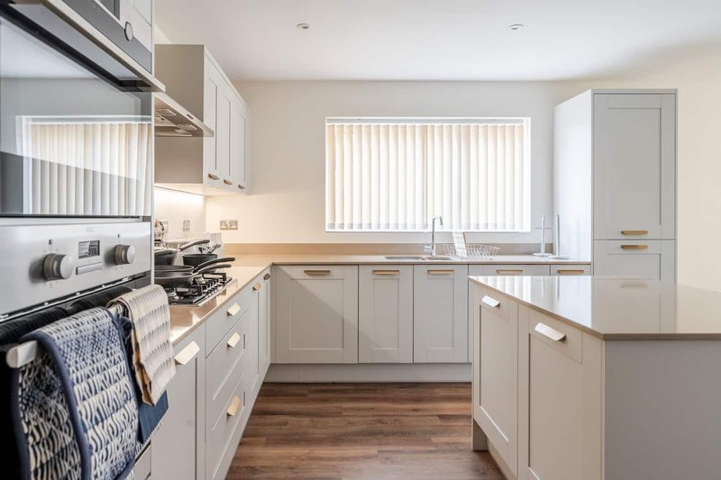 Modern kitchen with white cabinetry, wooden worktops, stainless steel appliances and vertical blinds