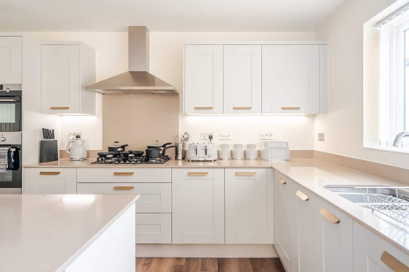 Modern white kitchen with island, gas hob, extractor hood and wooden worktops