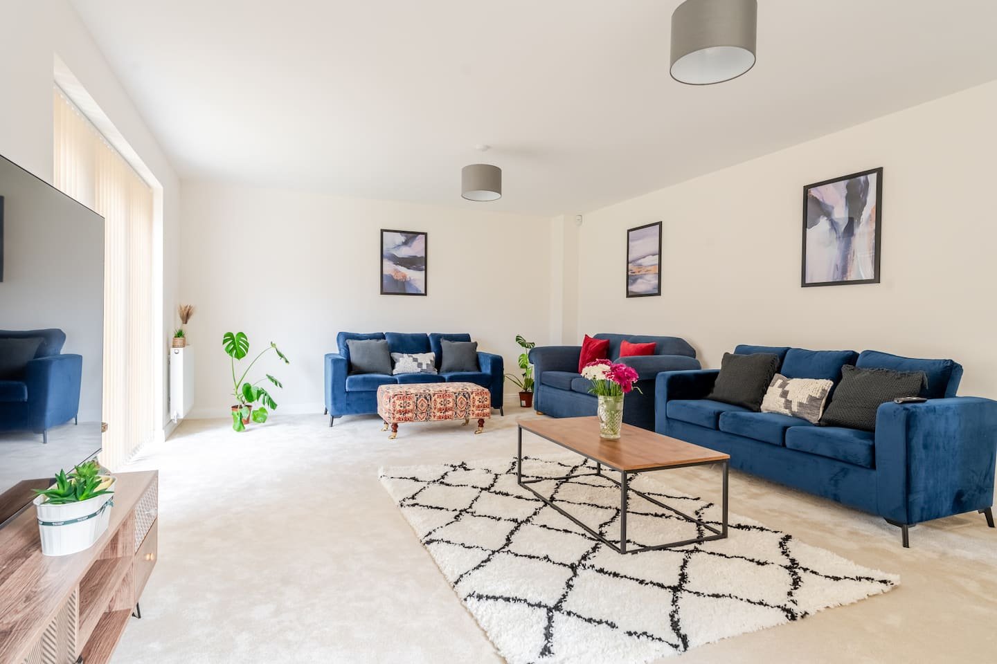 Spacious living room with blue sofas, wooden coffee table, patterned rug and framed wall art