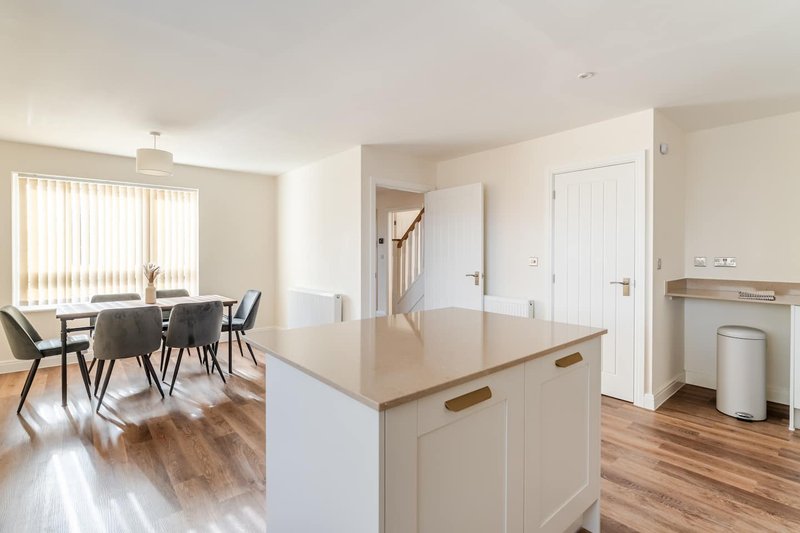 Open-plan kitchen and dining area with white cabinetry, wooden flooring, and contemporary furnishings