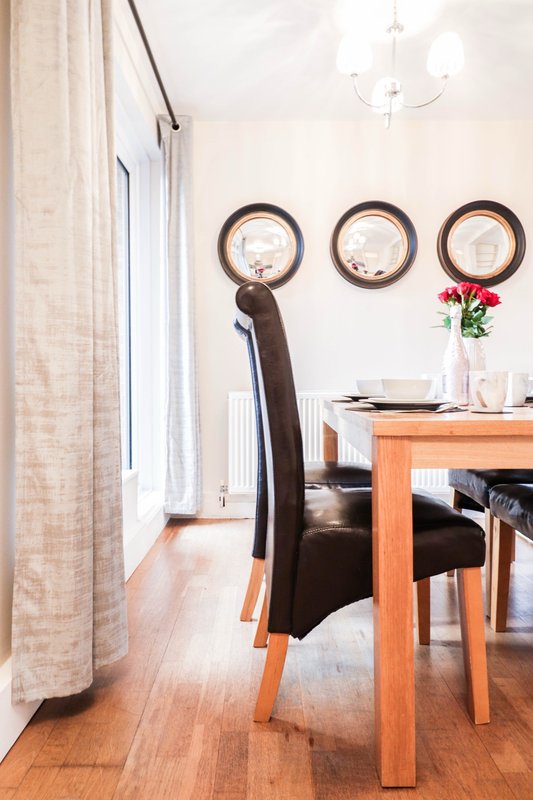 Dining area with wooden table, black chair, wall mirrors and pendant light fixture