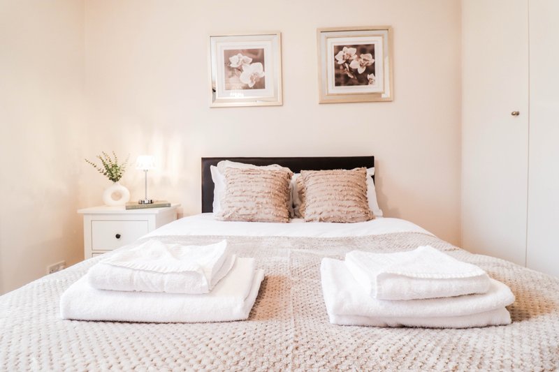 Bedroom with double bed, fresh white towels, black headboard, framed photos on wall