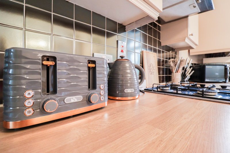 Modern kitchen with black and copper toaster, kettle, and small appliances on wooden countertop
