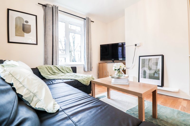 Bright bedroom with double bed, wooden desk, TV, framed wall art and large window